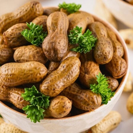 Boiled peanuts in a bowl, garnished with fresh parsley.