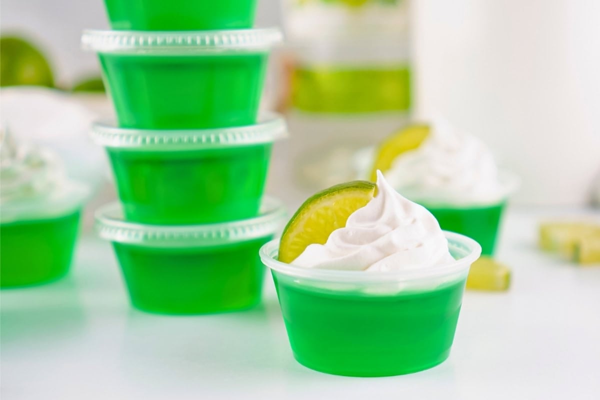 Green gelatin in small cups, topped with whipped cream and lime slices.
