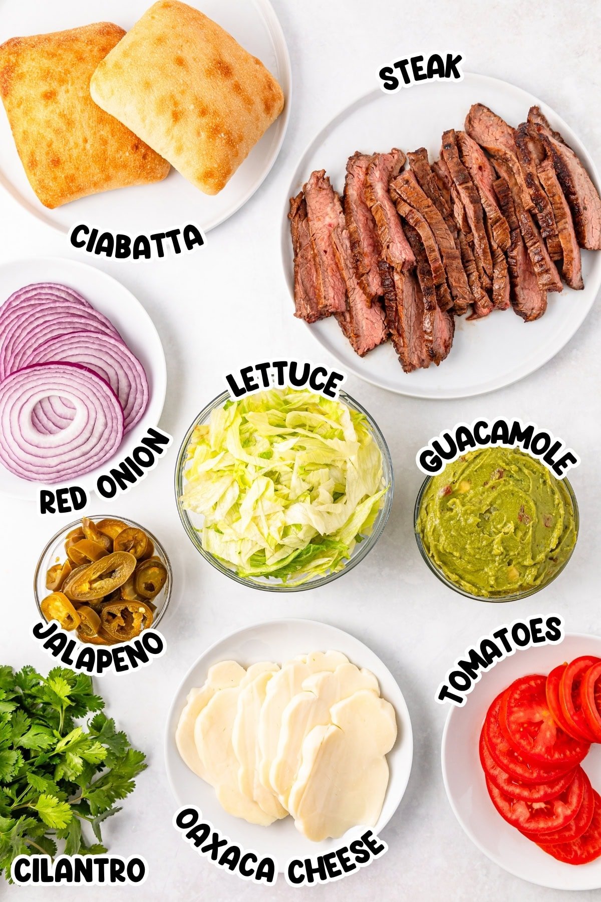 Sandwich ingredients: steak, ciabatta, guacamole, cheese, lettuce, tomato, onion.