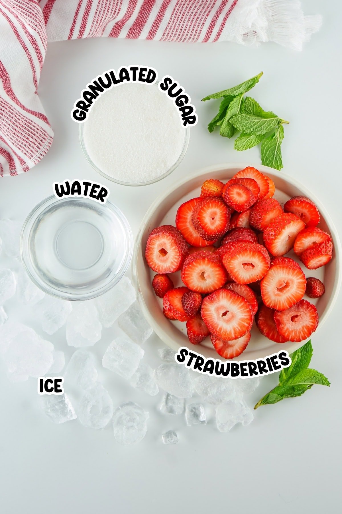 Bowl of sliced strawberries, ice cubes, water, sugar, and mint on a white surface.