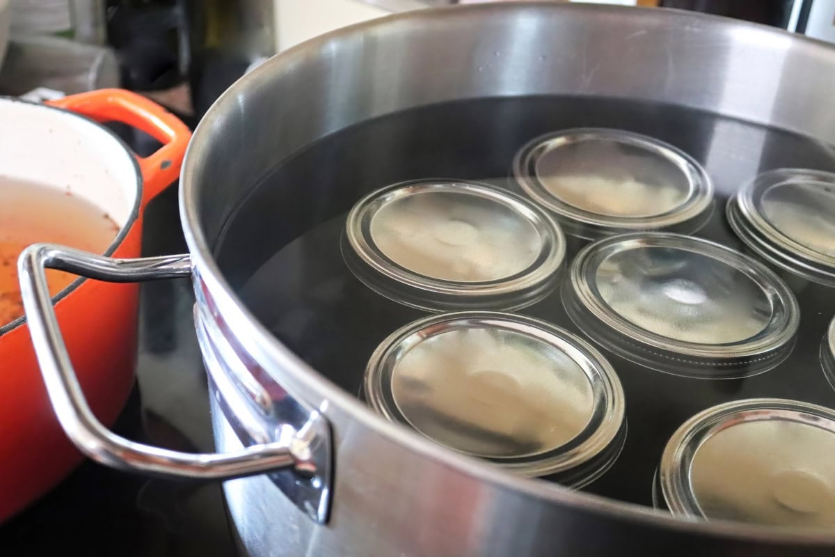 Mason jars submerged in water inside a large pot for canning.