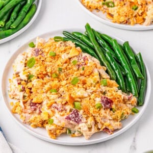 A plate of creamy casserole topped with crumbs, served with fresh green beans.
