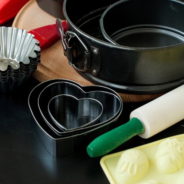 Assorted baking tools, best baking pan, heart cutters, and a rolling pin on a table.