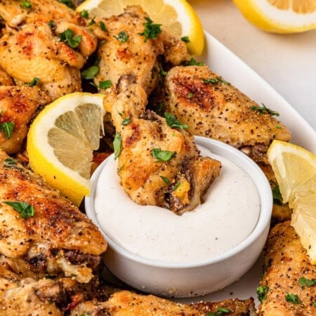Game day food on a budget: Lemon pepper chicken wings with lemon slices and dip.