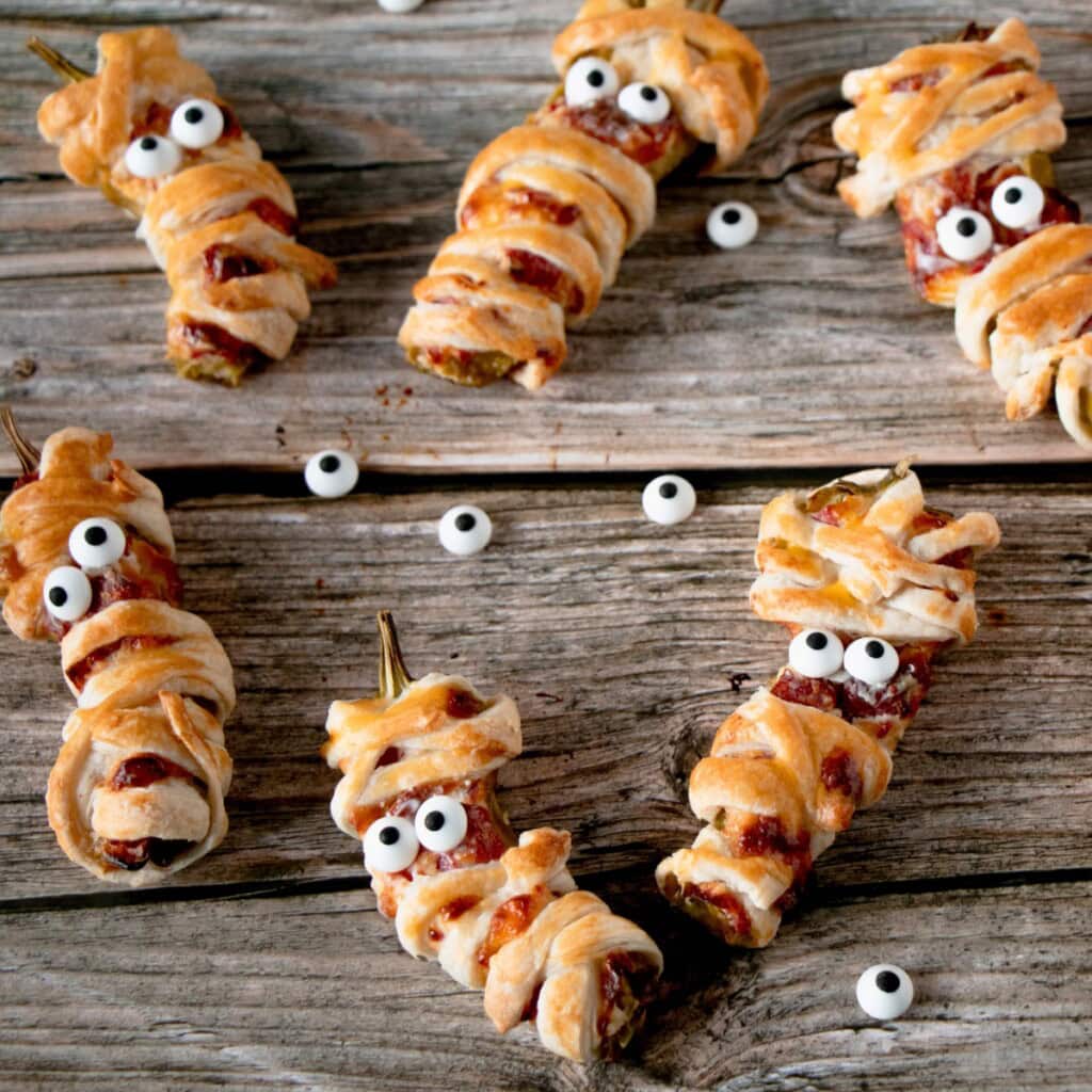 Jalapeño popper mummies spooky adult Halloween party ideas on a rustic table.