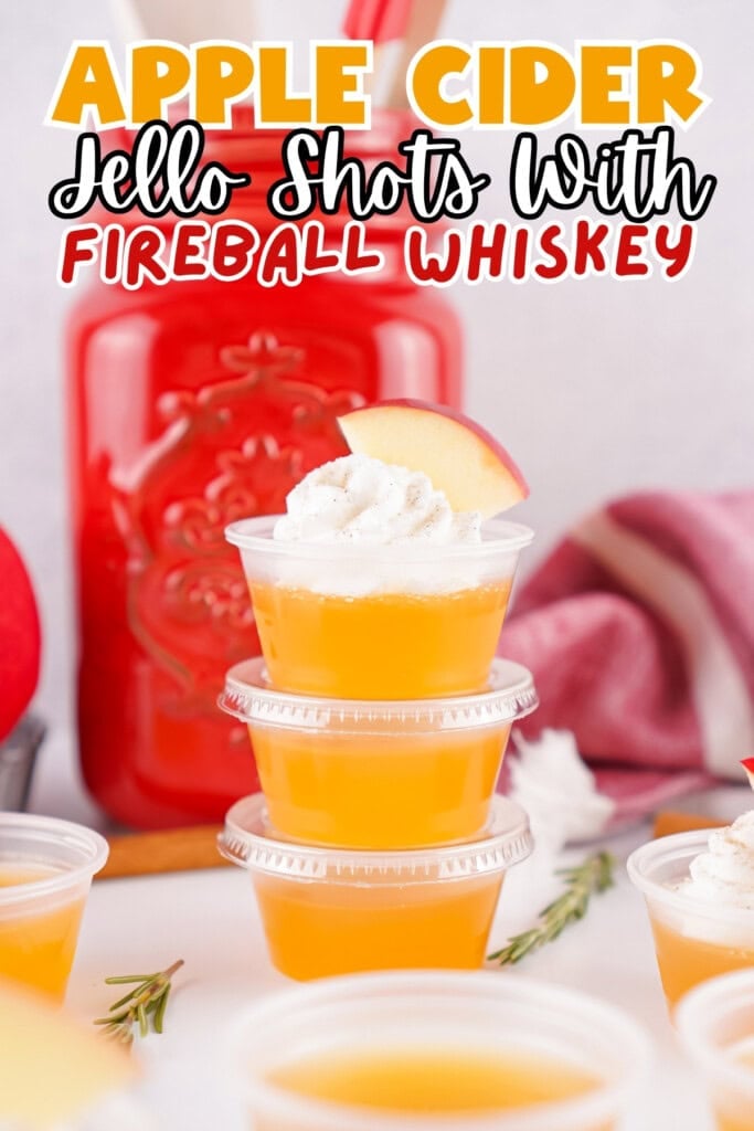 Three apple cider Jello shots topped with whipped cream and apple slices.