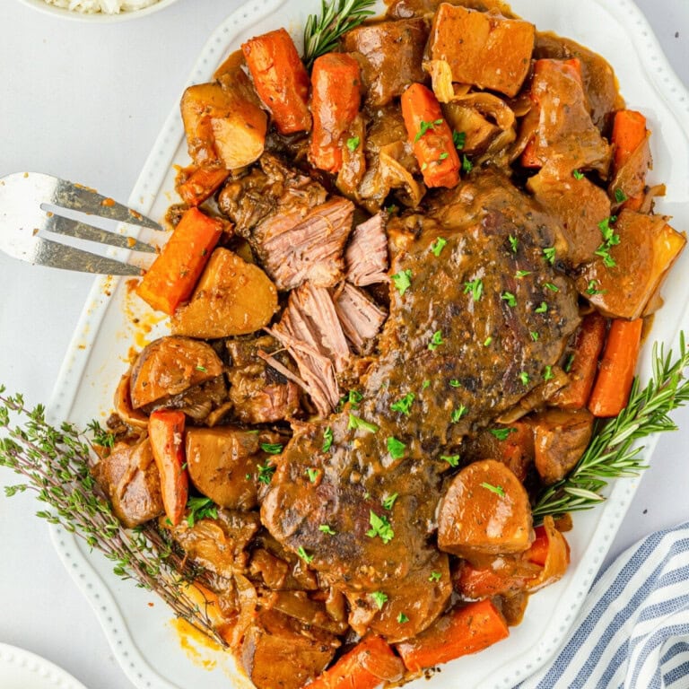 Make-ahead Thanksgiving pot roast with carrots and potatoes on a white platter.