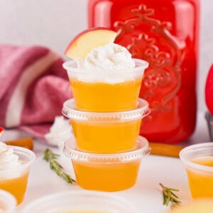 Three stacked Apple Cider Jello Shots topped with whipped cream and apple slice.