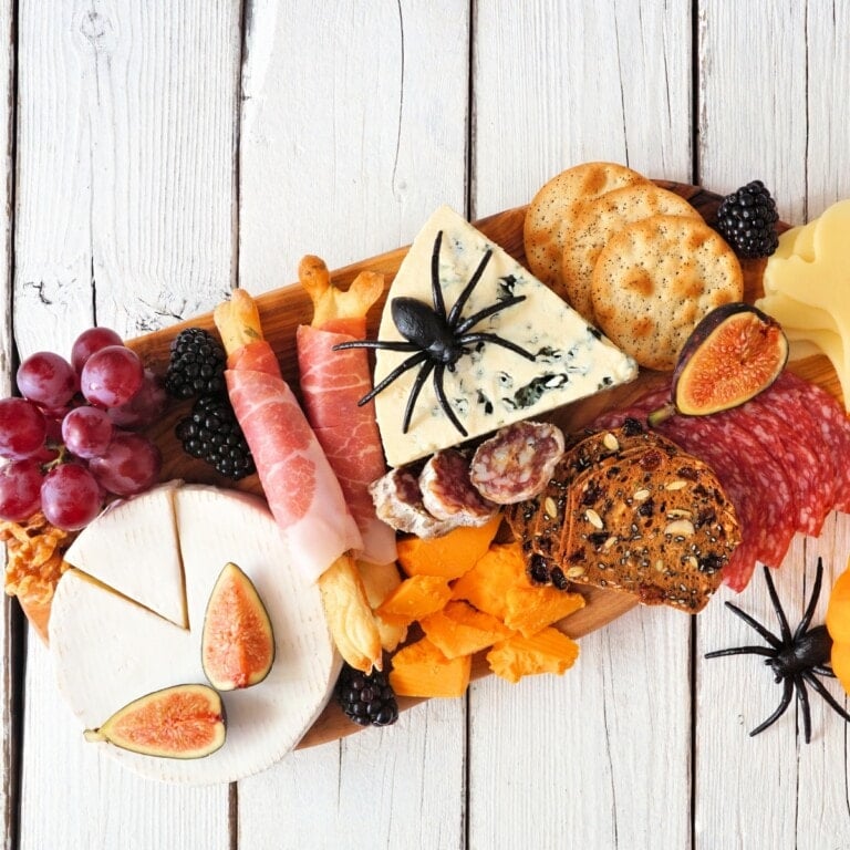 Halloween Charcuterie Board with cheese, figs, crackers, and spooky fake spiders.