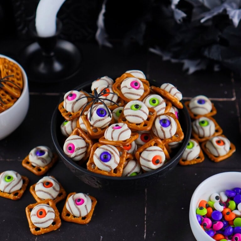 Bowl of Halloween pretzel treats topped with white chocolate and candy eyes.