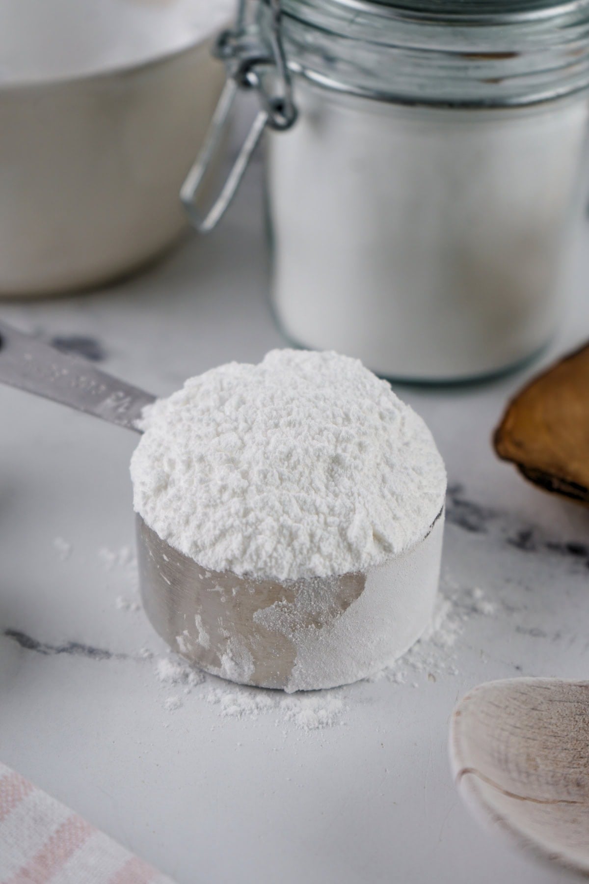 A metal measuring cup filled with flour on a kitchen counter.