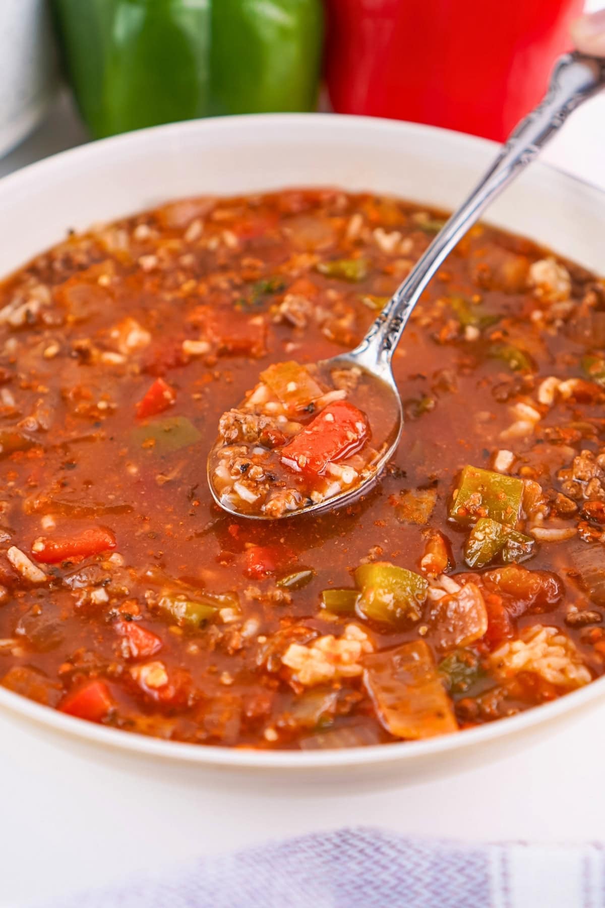 A bowl of hearty soup with rice, ground meat, and colorful bell peppers.