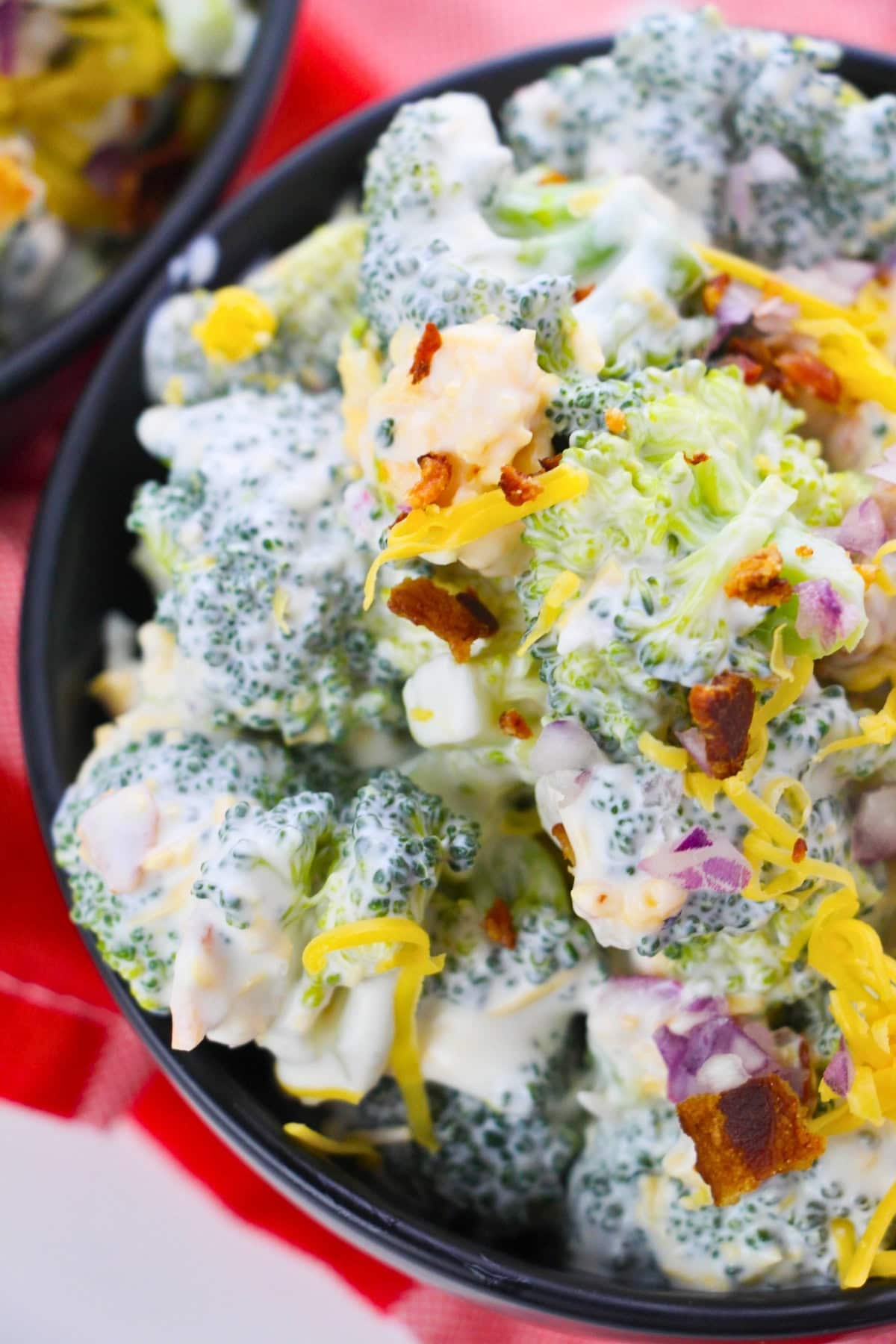 Broccoli salad with creamy dressing, shredded cheese, bacon, and red onion.