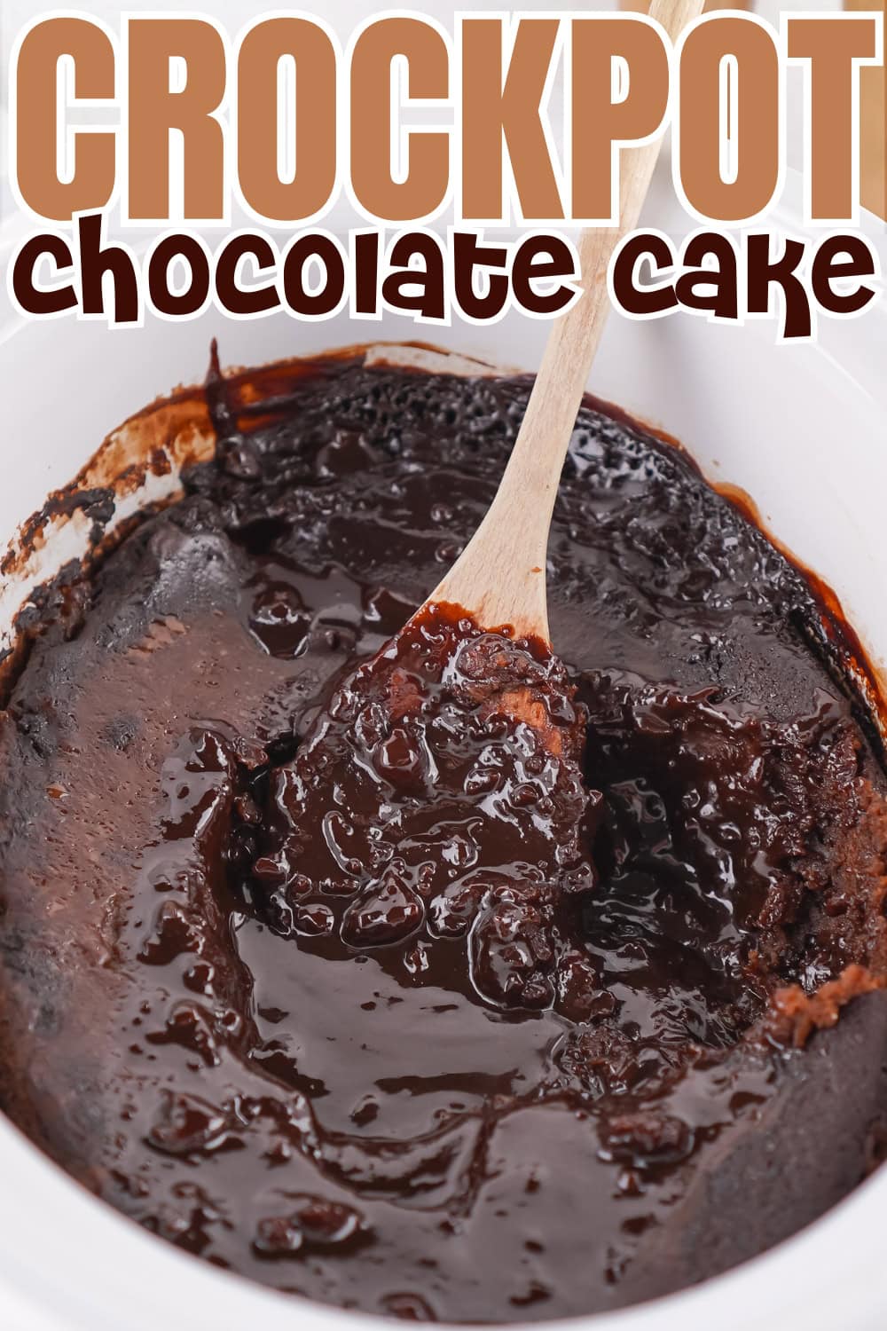 A wooden spoon scoops gooey chocolate cake from a crockpot.