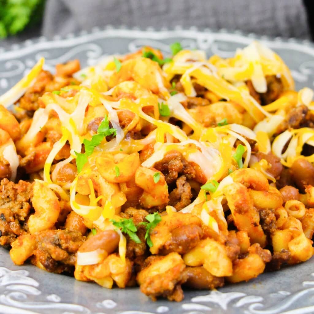 A plate of cheesy beef and macaroni topped with shredded cheese and herbs.