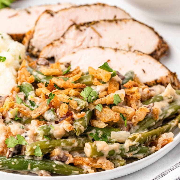 Green bean casserole topped with crispy onions, served with sliced roast turkey.