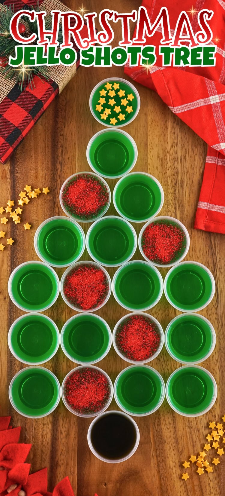 Green jello shots arranged in a Christmas tree shape on a wooden table.
