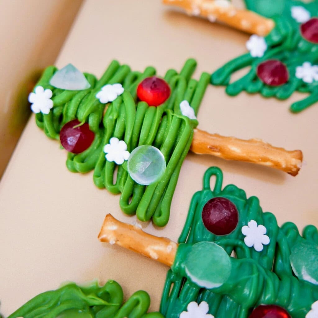 Christmas tree-shaped treats made of pretzels, green icing, and colorful candies.