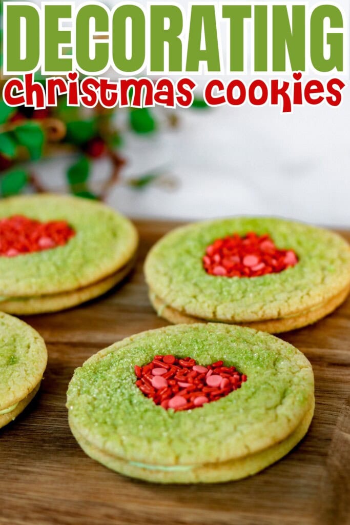 Green Christmas cookies with red heart centers on a wooden surface.