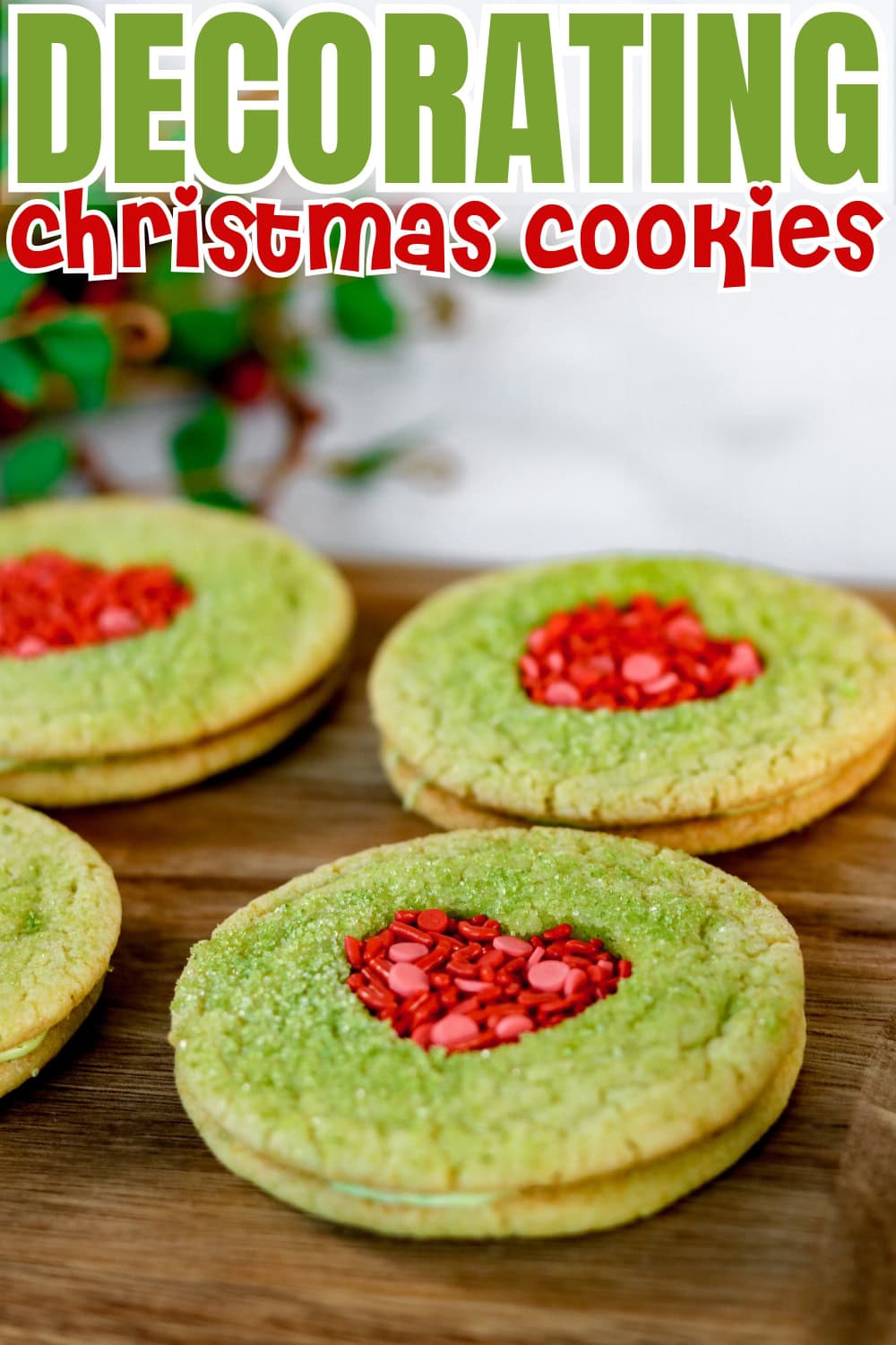 Green Christmas cookies with red heart centers on a wooden surface.