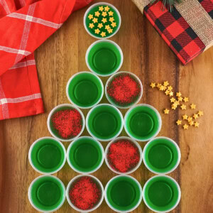 Jello Shot Christmas Tree cups arranged with red sprinkles and festive stars.