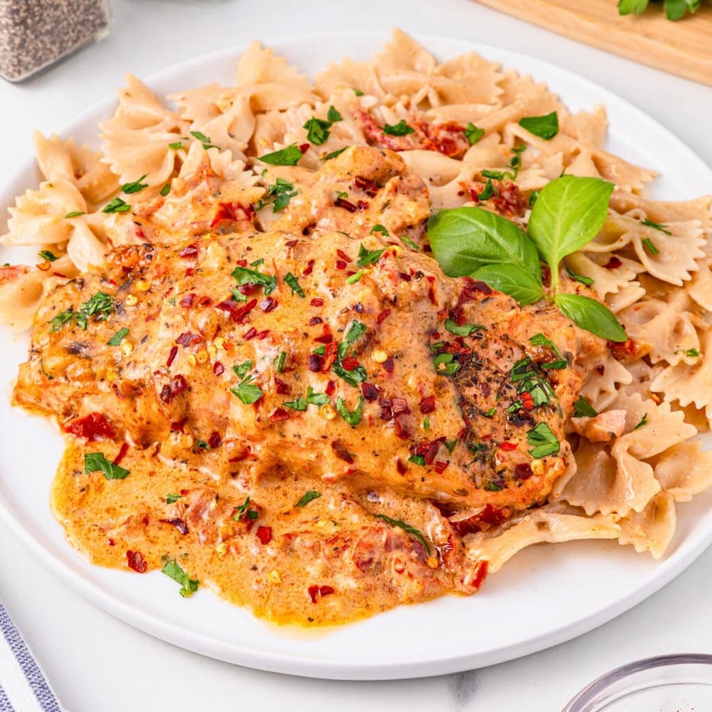 Pasta with creamy, herb-seasoned chicken garnished with basil and parsley.