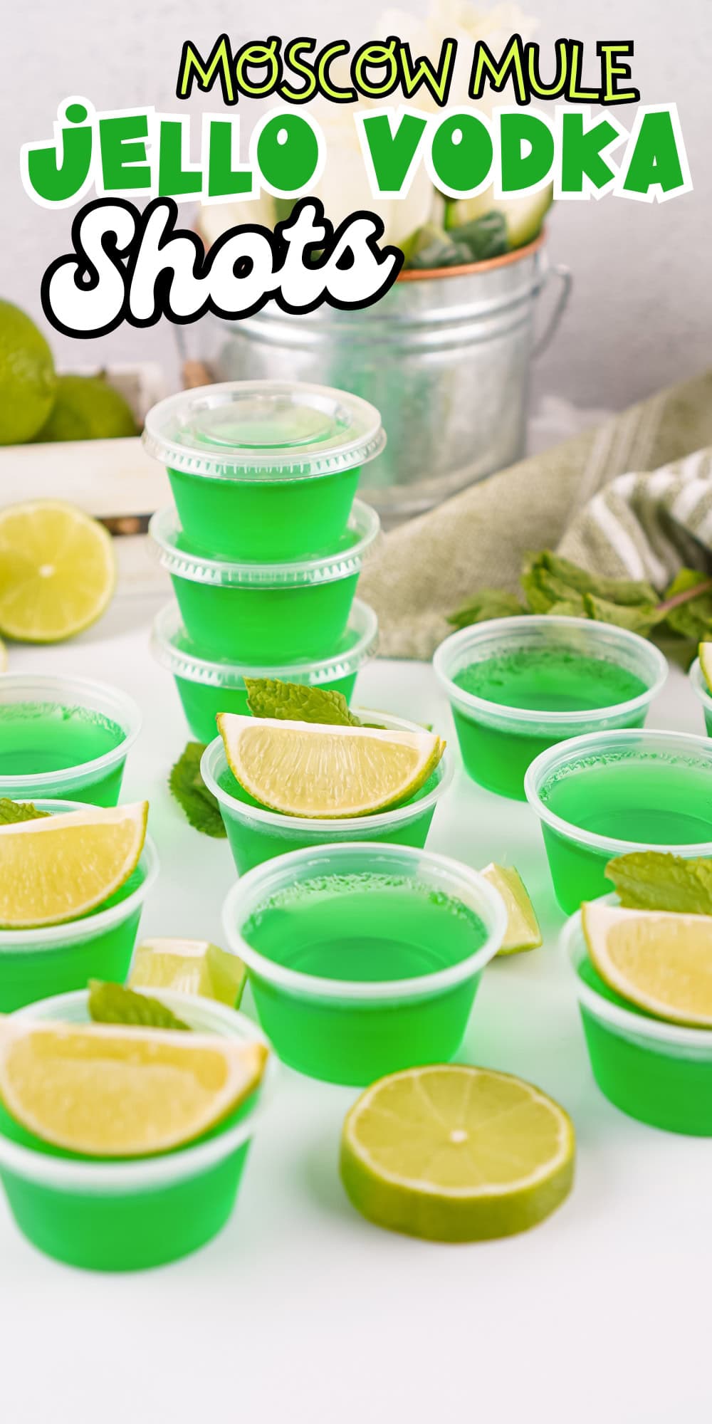 Green jello vodka shots with lime wedges and mint.