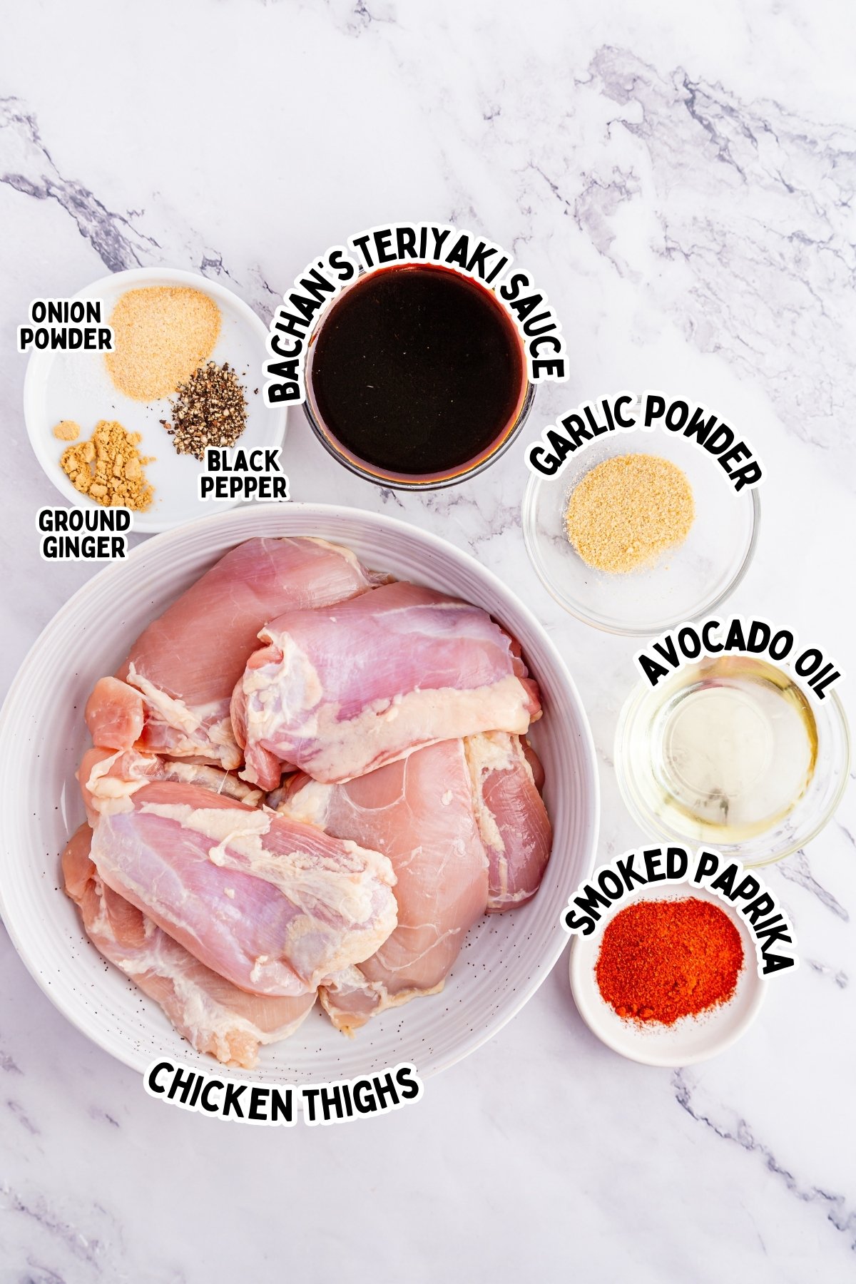 Raw chicken thighs in a bowl with seasonings, sauce, and oil in small dishes nearby.