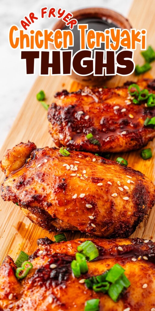 Glazed chicken thighs with green onions and sesame seeds on a wooden board.