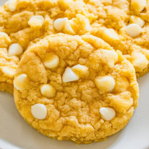 Chewy cookies with white chocolate chips on a white plate.