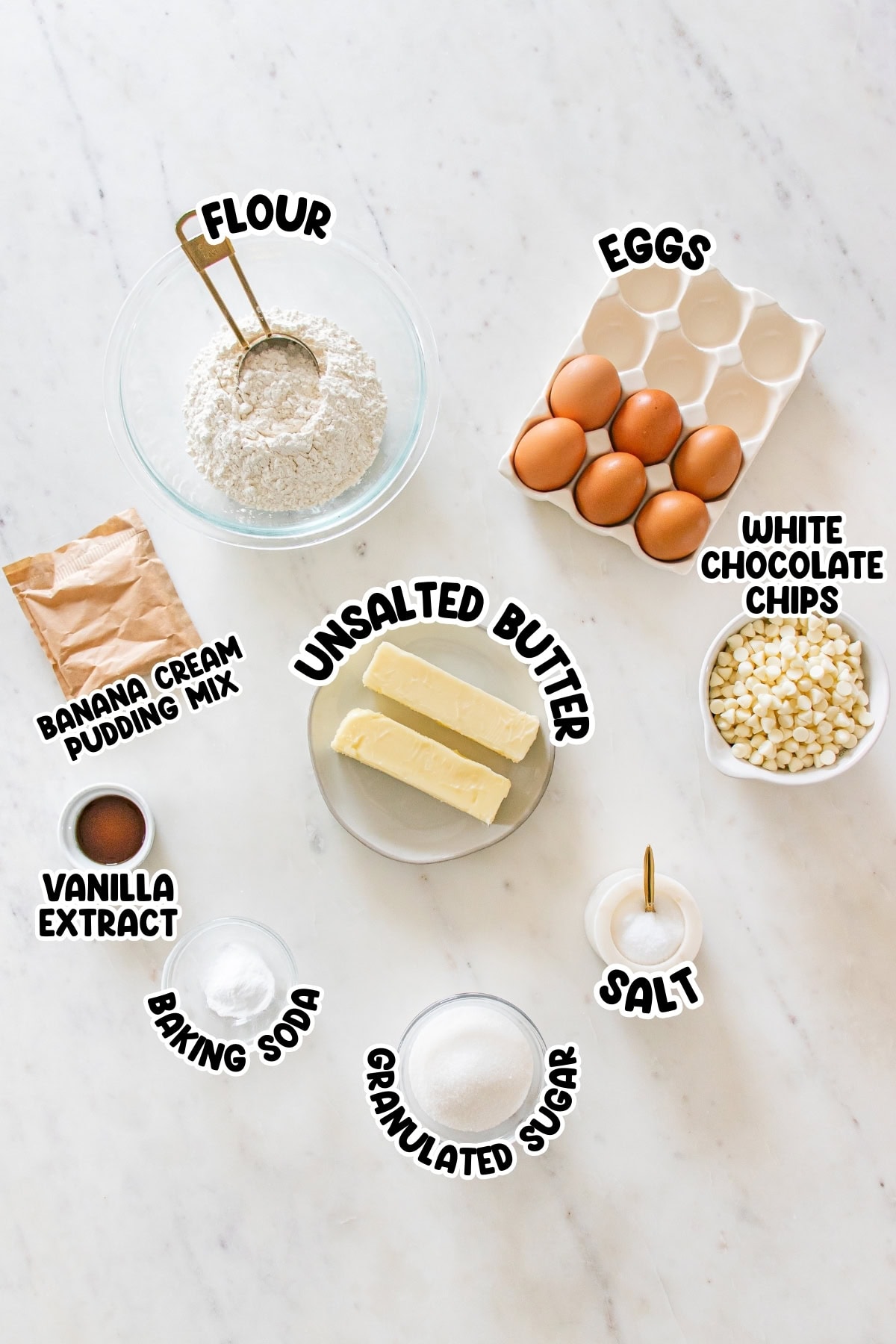 Baking ingredients labeled on a white surface, including flour, eggs, and butter.