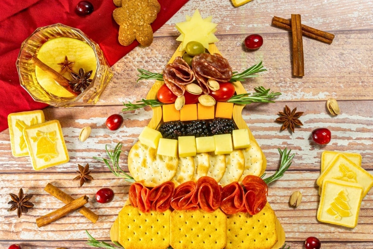Charcuterie board arranged as a Christmas tree with crackers, cheese, and meats.