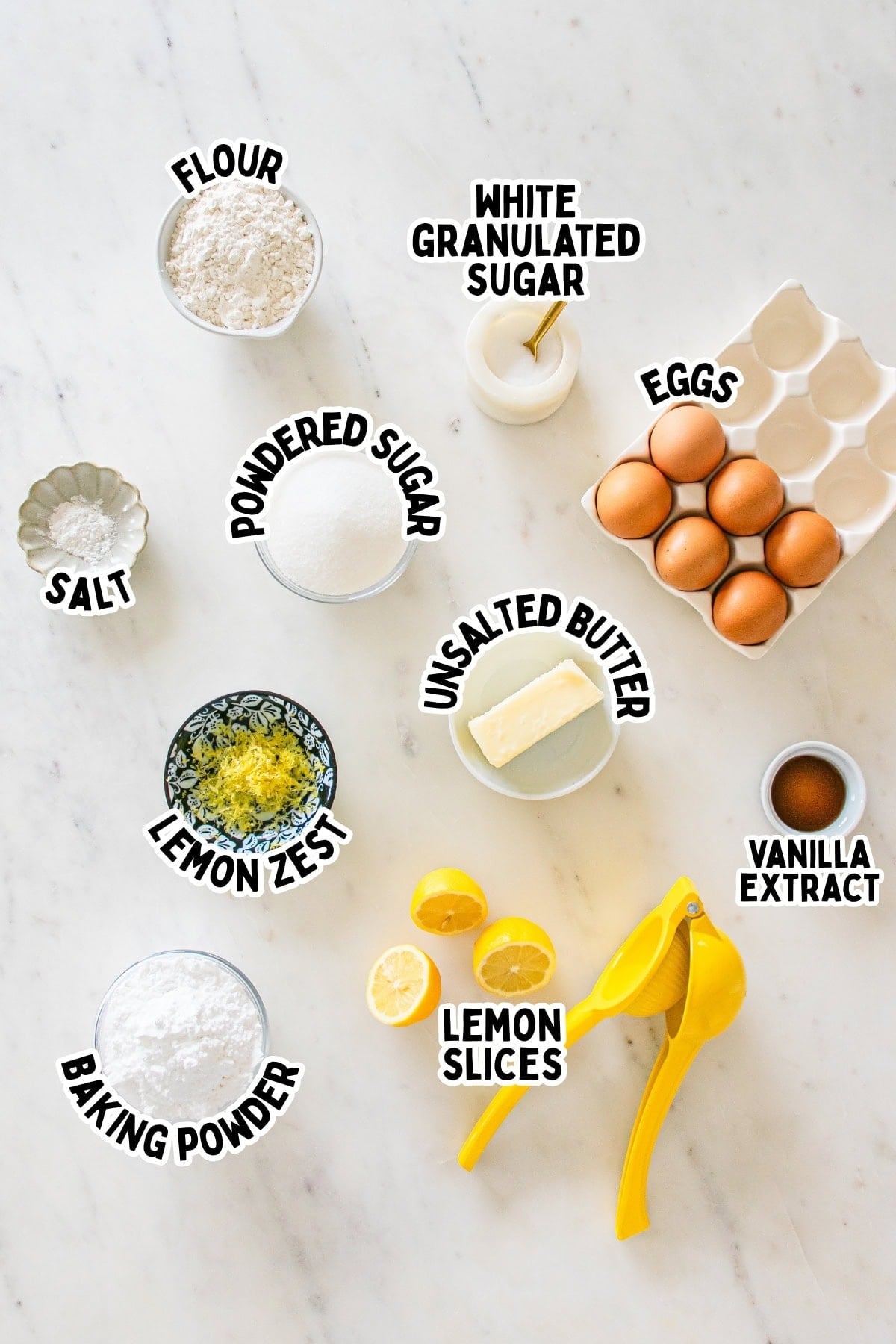 Baking ingredients labeled on a marble surface, including eggs, flour, butter, and lemon.