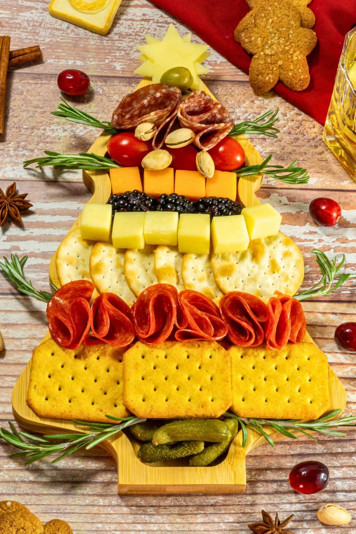 Christmas tree-shaped charcuterie board with meats, cheeses, crackers, and garnish.