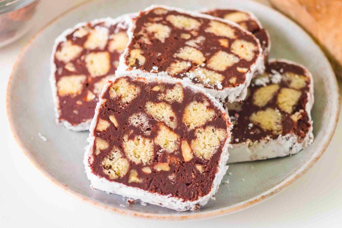 Four slices of chocolate biscuit cake on a plate, dusted with powdered sugar.