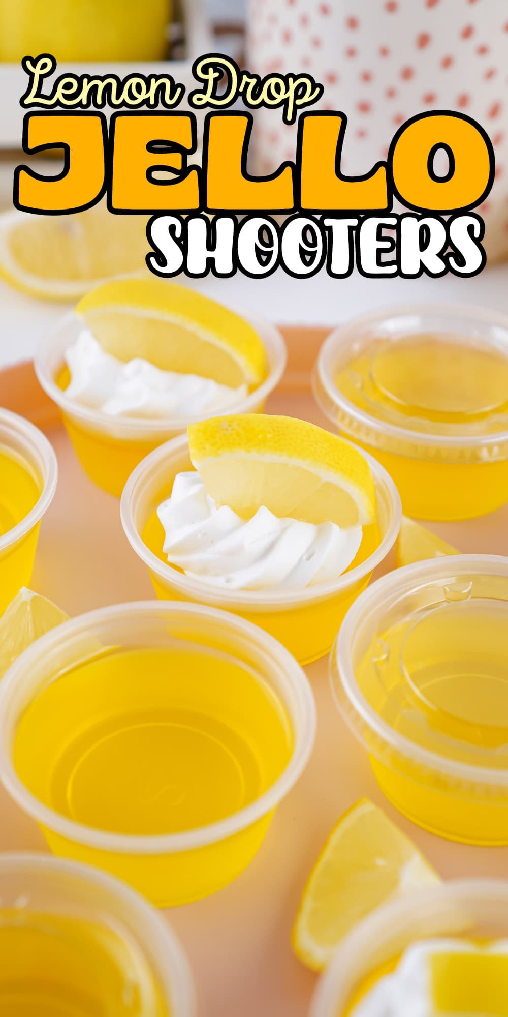 Yellow jello shooters in cups, some topped with whipped cream and lemon slices.