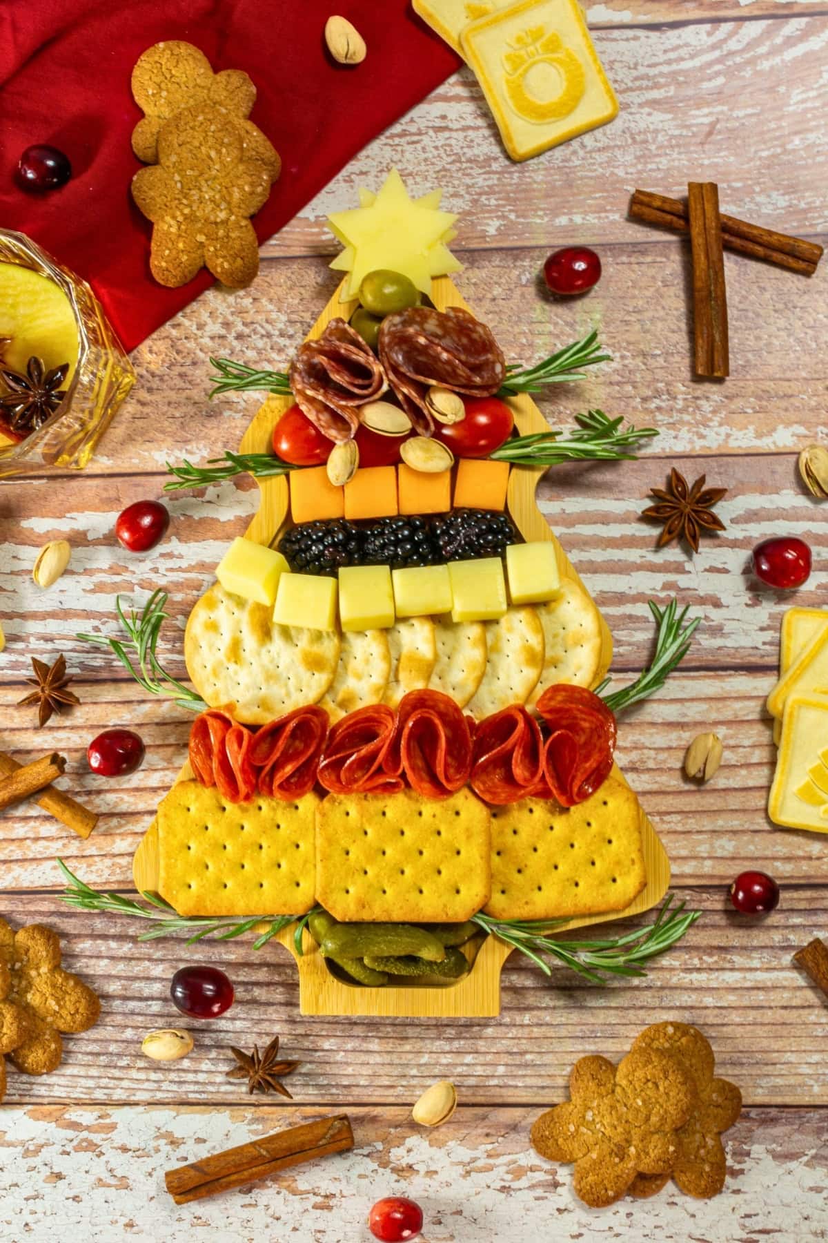 Charcuterie board arranged as a Christmas tree with crackers, cheese, and meats.