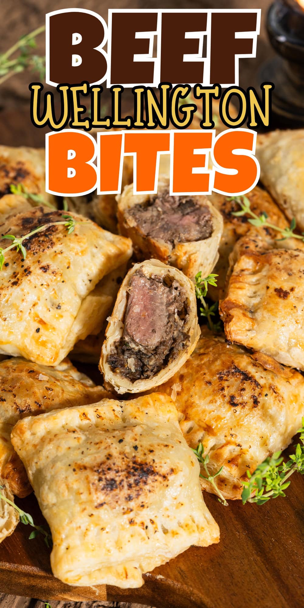 Golden, flaky beef Wellington bites arranged on a wooden board with herbs.