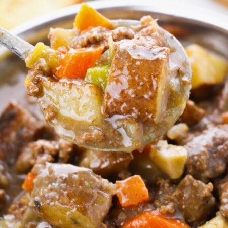 A spoonful of hearty beef stew with potatoes, carrots, and celery.
