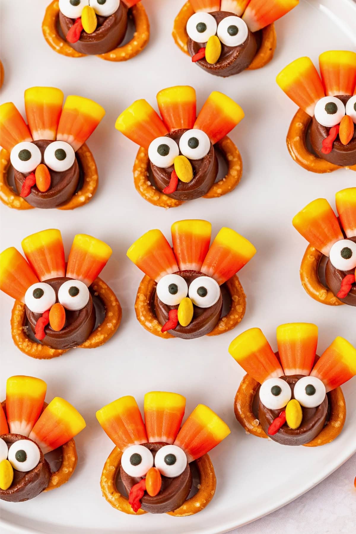 Candy turkeys made with pretzels, chocolate, candy corn, and candy eyes on a plate.