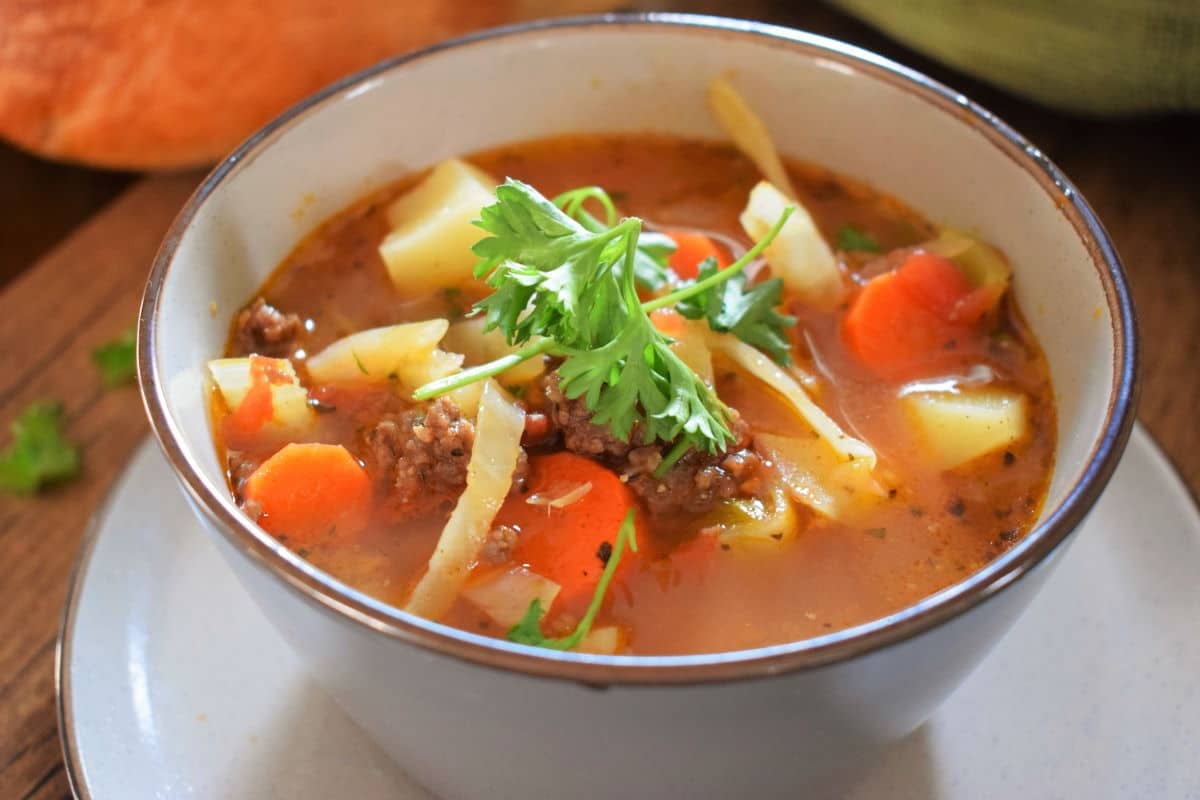 Bowl of vegetable and beef soup garnished with fresh parsley.