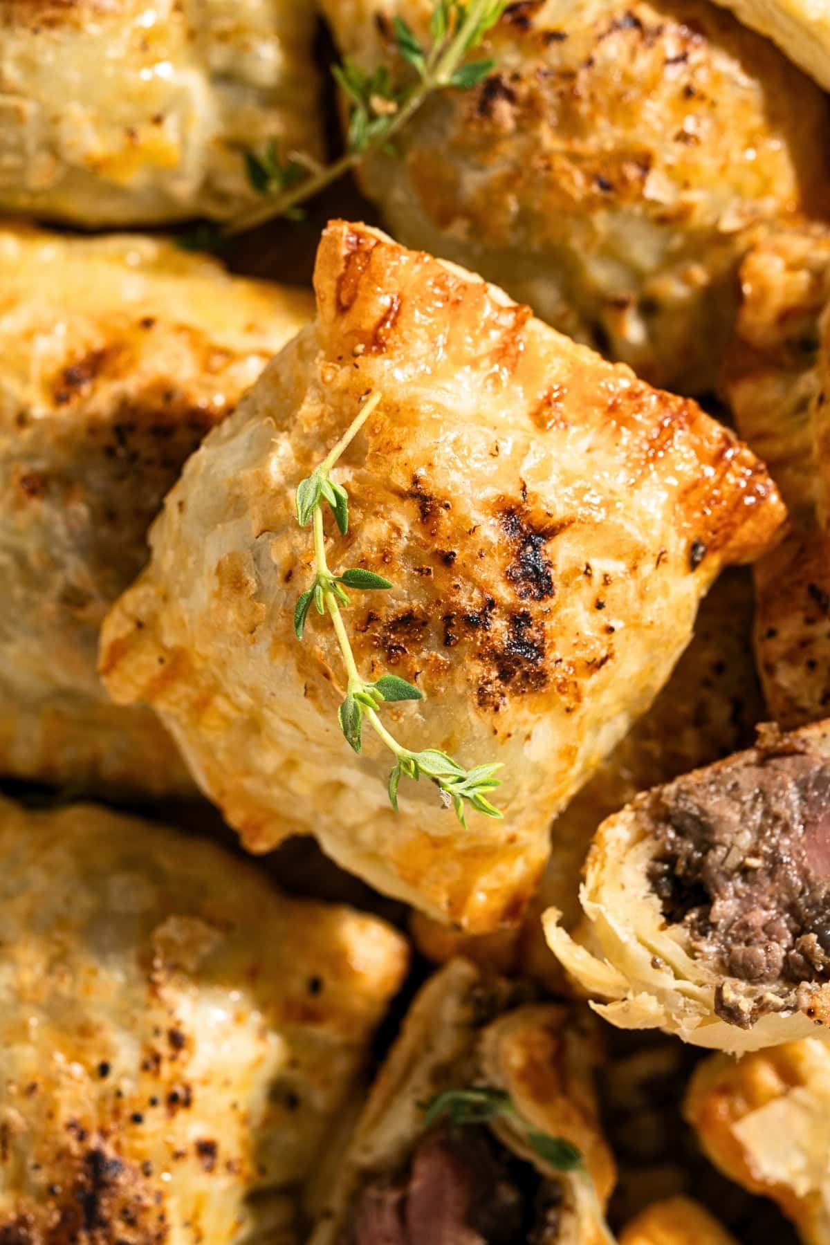 Golden puff pastry parcels garnished with fresh thyme, some with savory filling.