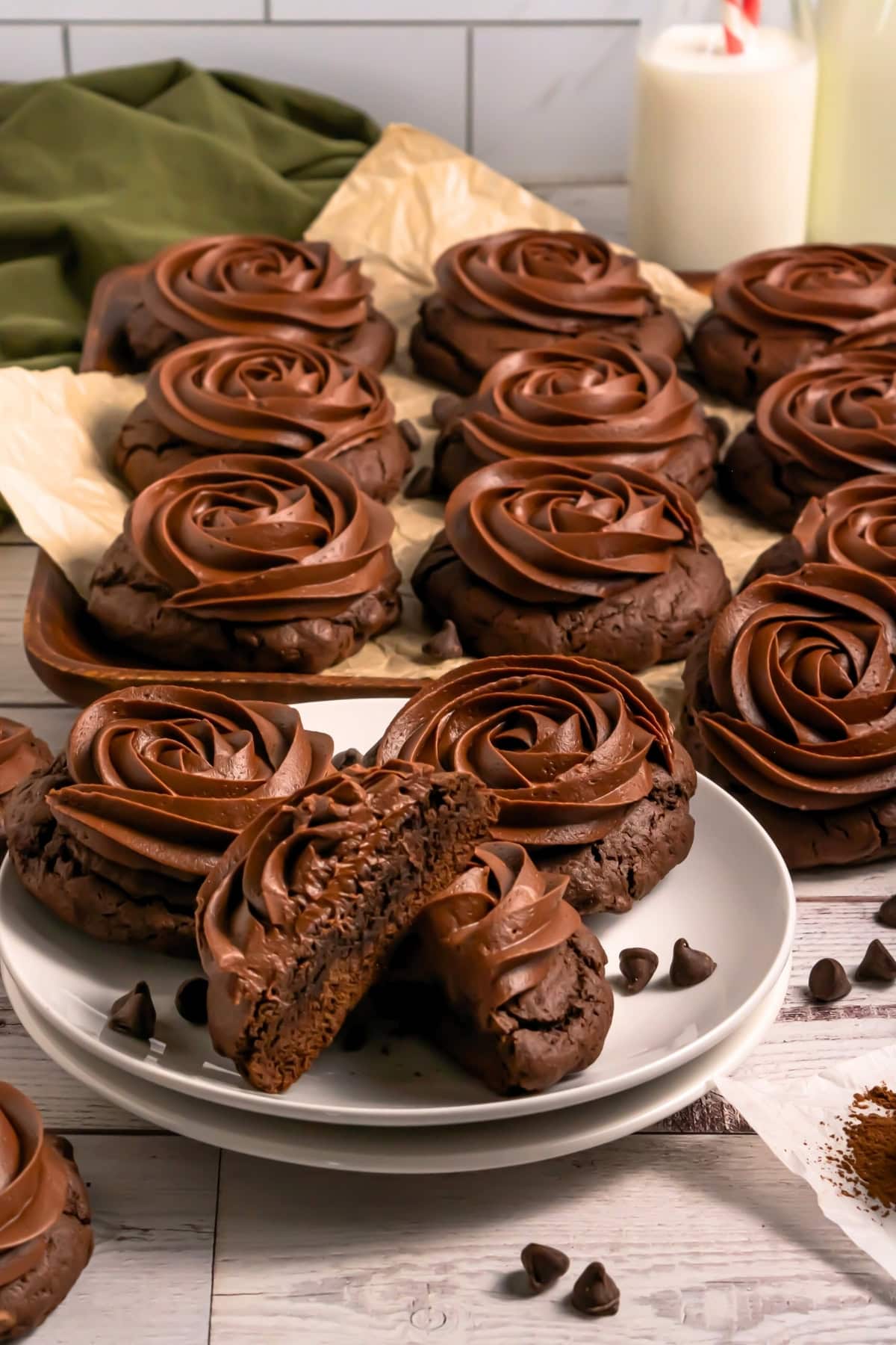Chocolate cookies with swirled chocolate frosting on a plate and tray.