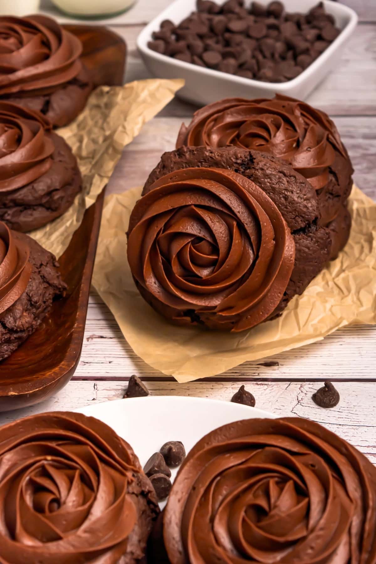Thick chocolate cookies topped with swirled chocolate frosting on parchment paper.