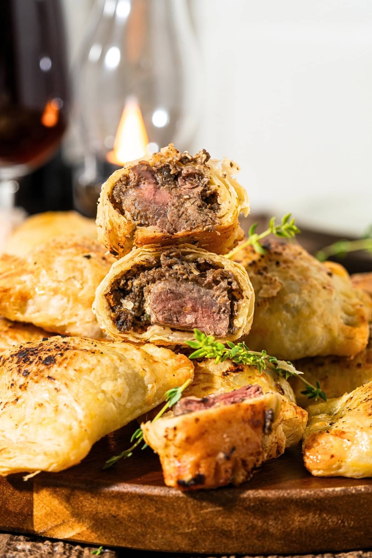 Golden, flaky pastry stuffed with juicy beef, stacked on a wooden board.