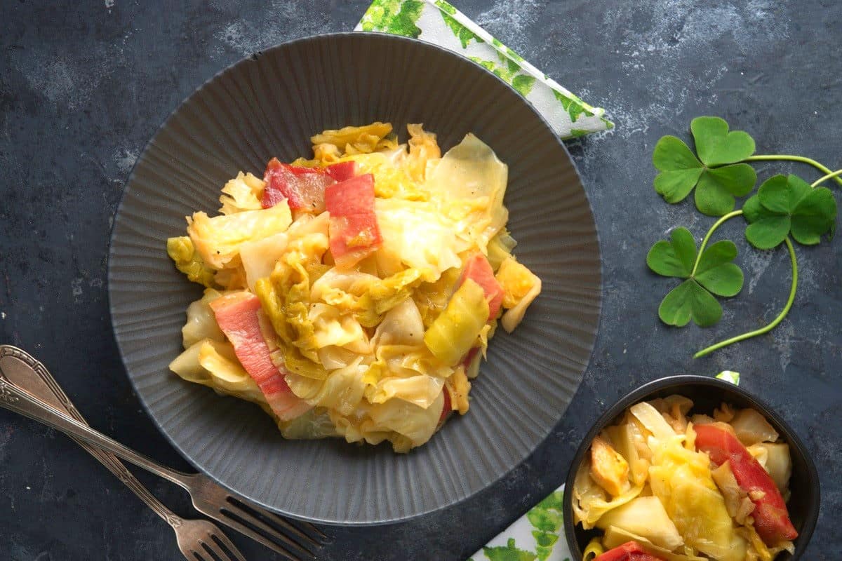 A plate of cooked cabbage and corned beef, with a napkin and shamrock nearby.