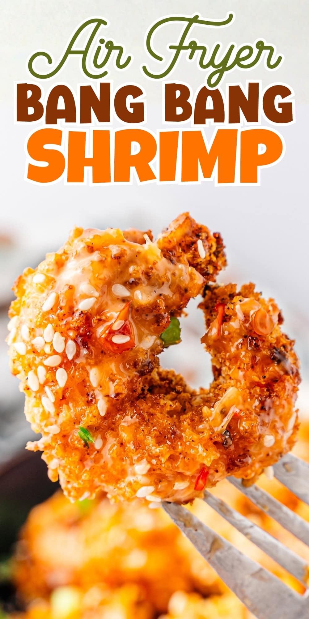 Crispy breaded shrimp on a fork, topped with sesame seeds.