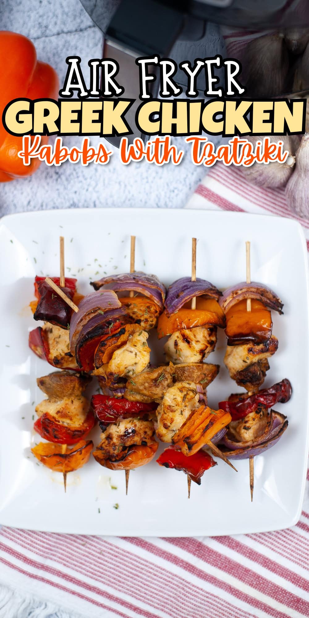 Greek chicken kabobs with peppers and onions on a white plate, striped cloth under.