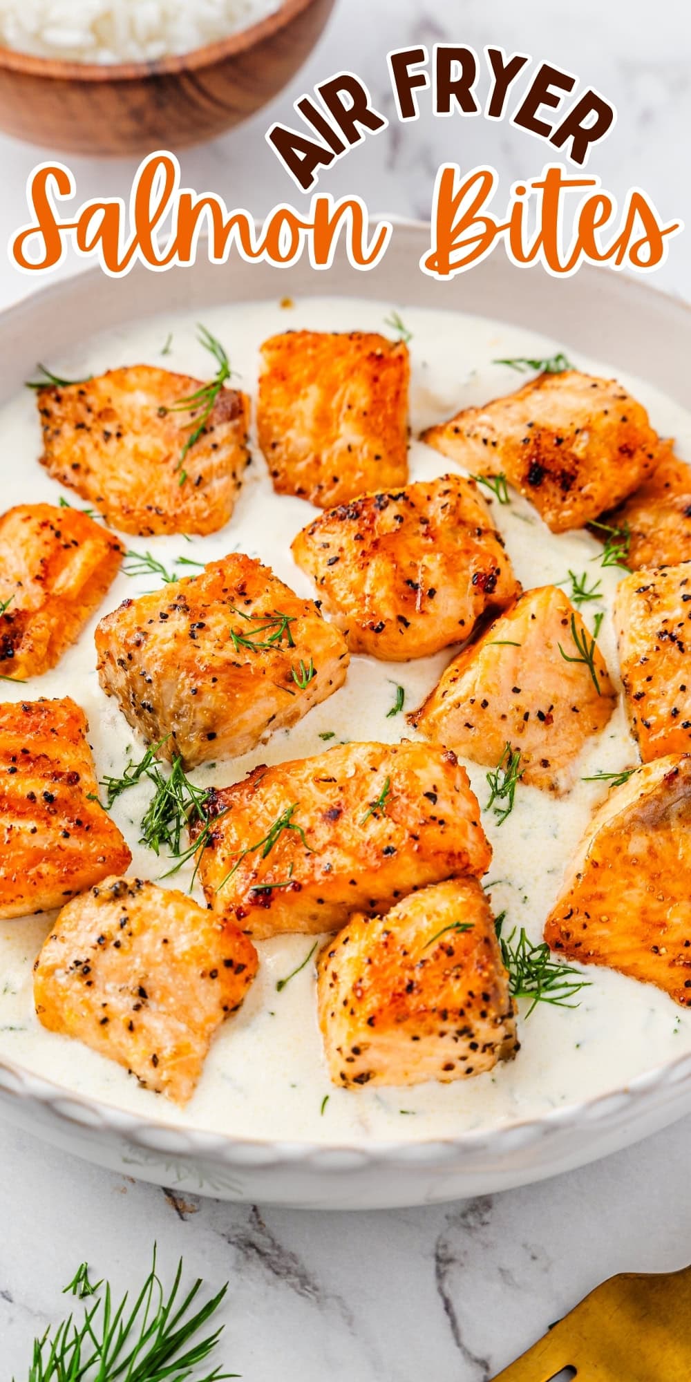 Salmon bites on a creamy sauce, garnished with fresh dill in a bowl.