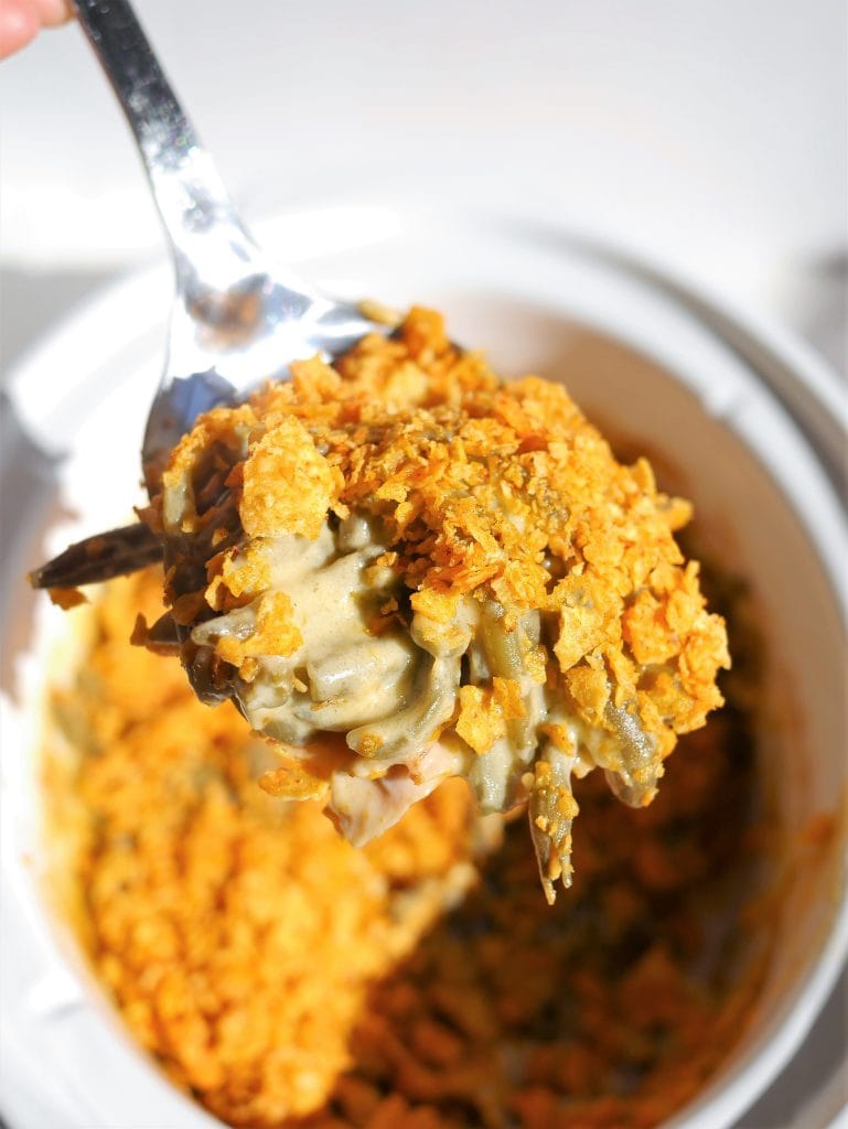 A fork holds a serving of creamy casserole topped with crushed cornflakes.